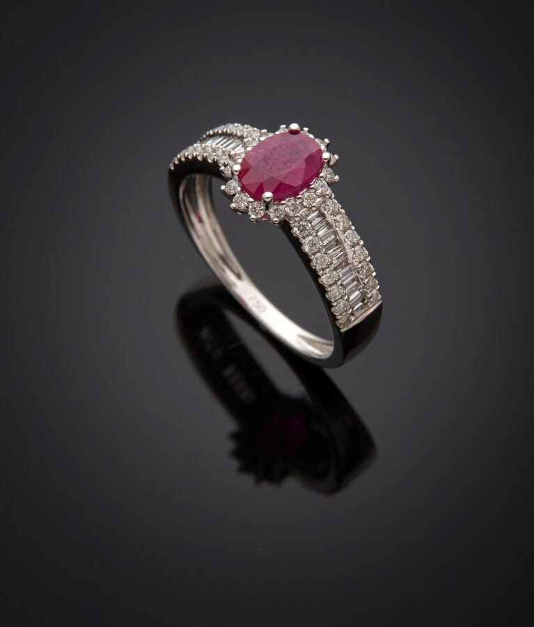 BAGUE en or gris (750‰) serti d'un rubis ovale, entouré et épaulé de diamants t…