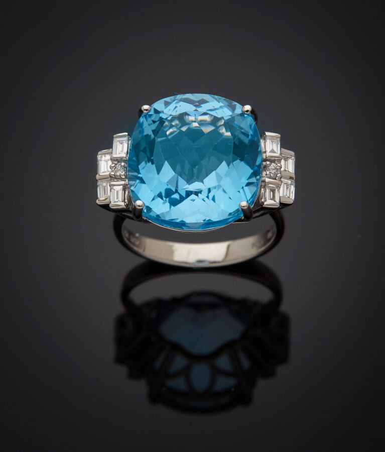 BAGUE en or gris (750‰) serti d'une topaze bleue taille coussin, épaulée de dia…