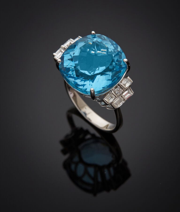 BAGUE en or gris (750‰) serti d'une topaze bleue taille coussin, épaulée de dia…