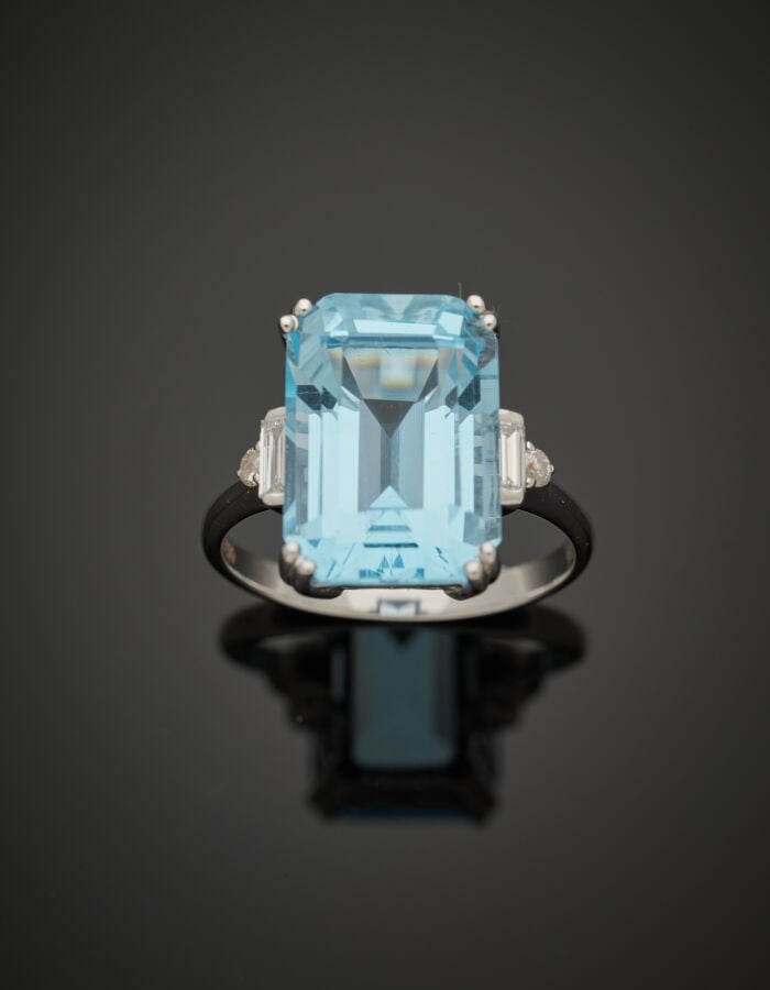 BAGUE en or gris (750‰) serti d'une topaze bleue taillée à degrés, épaulée de d…