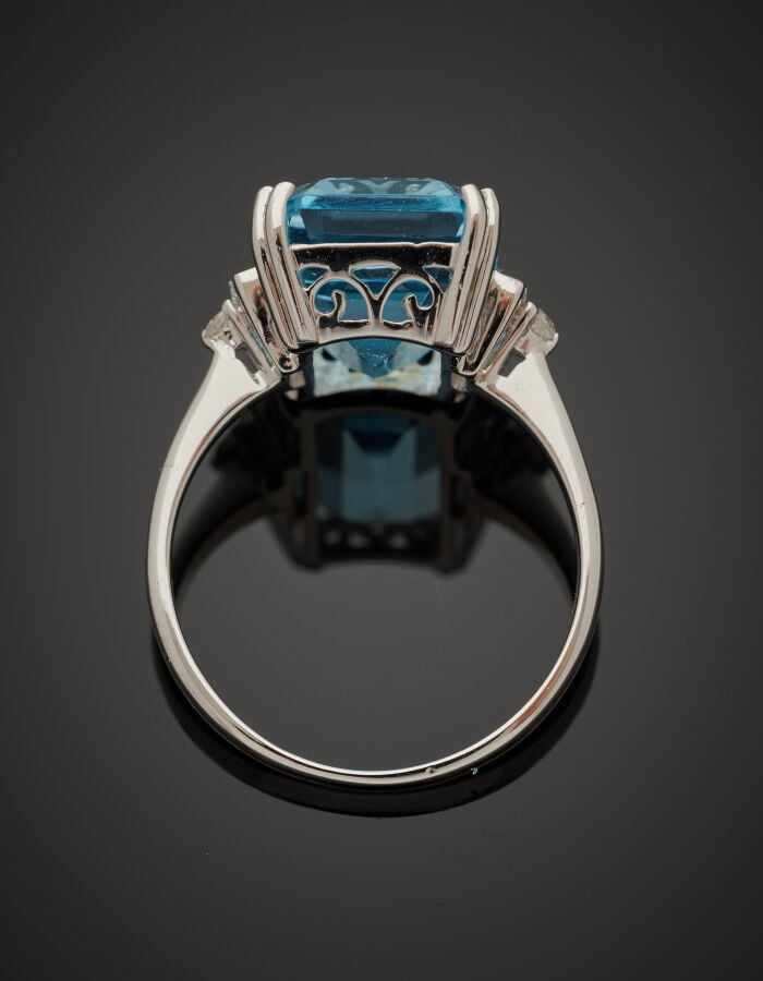 BAGUE en or gris (750‰) serti d'une topaze bleue taillée à degrés, épaulée de d…