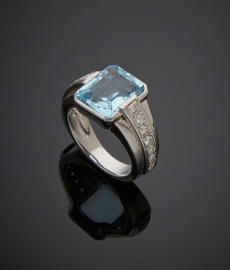 BAGUE en or gris (750‰) serti d'une topaze bleue taillée à degrés, épaulée de d…