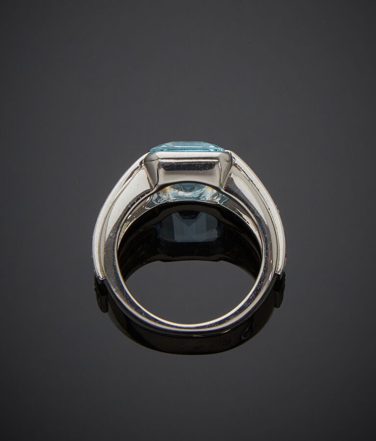 BAGUE en or gris (750‰) serti d'une topaze bleue taillée à degrés, épaulée de d…