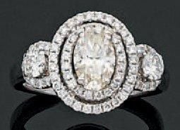 BAGUE en or gris ajouré serti d'un diamant central de forme ovale dans un double entourage de diamants, épaulé de deux diamants taille brillan