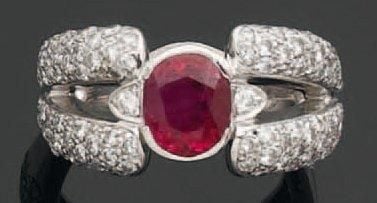 BAGUE en or gris ajouré serti d'un rubis central de forme ovale épaulé de diamants taille brillan