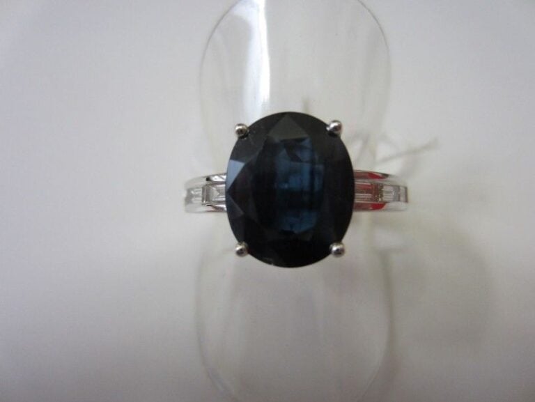 BAGUE en or gris ajouré serti d'un saphir de forme ovale épaulé de lignes de diamants baguette