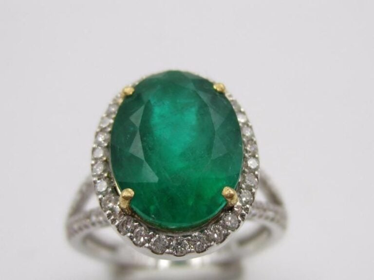 BAGUE en or gris et or jaune (750 millièmes) ajouré serti d’une émeraude, pesant 4,84 carats, de forme ovale entourée et épaulée de lignes de diamants taille brillan