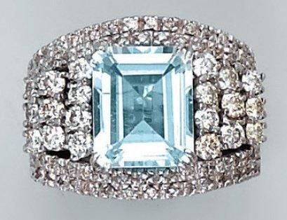 BAGUE en or gris partiellement ajouré serti d'une aigue-marine taillée à degrés épaulée et entourée de diamants taille brillan