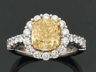 BAGUE en or gris serti d'un diamant Fancy Intense Yellow, de forme coussin, entouré et épaulé de diamants taille brillan