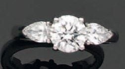 BAGUE en or gris serti d'un diamant taille brillant épaulé de deux diamants de forme poir