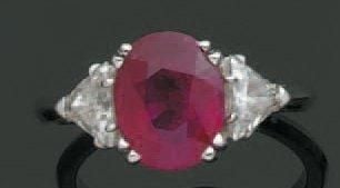 BAGUE en or gris serti d'un rubis 3,09 ct de forme ovale épaulé de deux diamants troïda