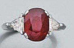 BAGUE en or gris serti d'un rubis de forme ovale pesant 2,38 carats épaulé de deux diamants troïdia