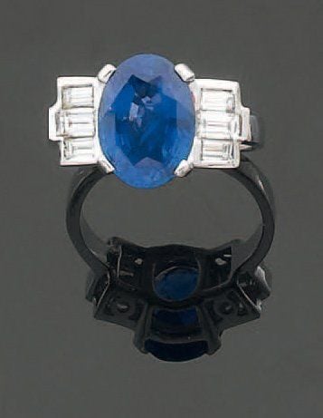 BAGUE en or gris serti d'un saphir de forme ovale épaulée de trois diamants baguettes de chaque côt