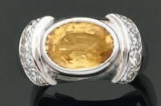 BAGUE en or gris serti d'un saphir jaune de forme ovale épaulé de huit diamants taille brillan