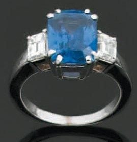 BAGUE en or gris serti d'un saphir pesant 4,64 ct de forme coussin épaulé de deux diamants taille émeraud