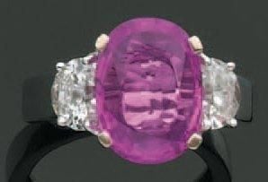 BAGUE en or gris serti d'un saphir rose pesant environ 4,40 carats, de forme ovale, épaulé de deux diamants demi-lun