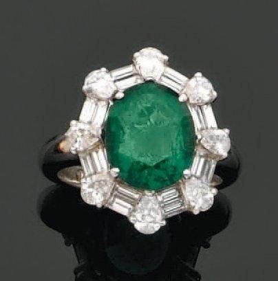 BAGUE en or gris serti d'une émeraude ovale entourée de diamants de forme poire et baguette alterné