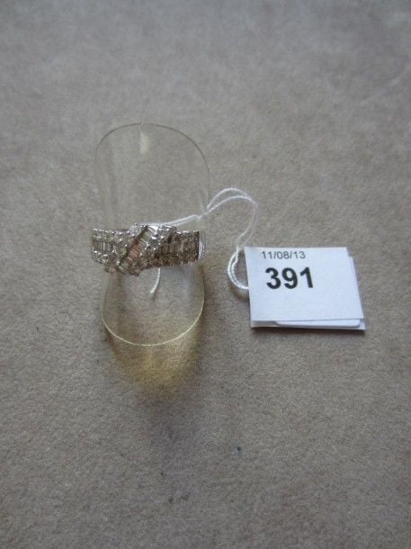 BAGUE en or gris serti de diamants taille baguette soulignés de diamants taille brillant et rehaussé d'une volut