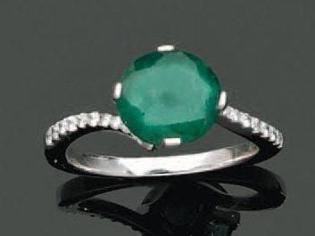 BAGUE en or gris sinueuse serti d'une émeraude ronde épaulée d'alignements de petits diamant