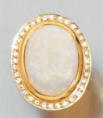 BAGUE en or jaune 14 carats (585 millièmes) serti d'une importante opale blanche de forme ovale entourée de diamants taille brillan