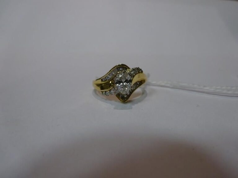 Bague en or jaune 18 k sertie d'un diamant central taille poire épaulé de diamants taille baguette et taille brillan