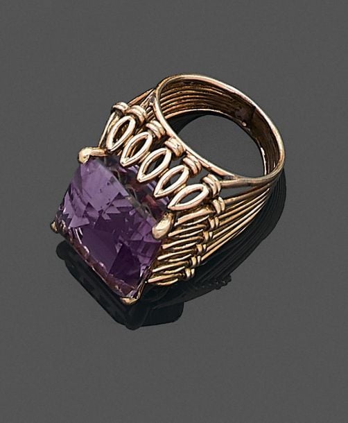 •BAGUE en or jaune (750‰) ajouré et filigrané, serti d'une importante améthyste taillée à degré