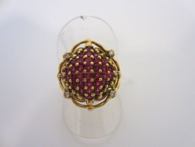 BAGUE en or jaune (750 millièmes), ajouré, serti d?un pavage de rubis calibrés et épaulé de quatre petits diamant