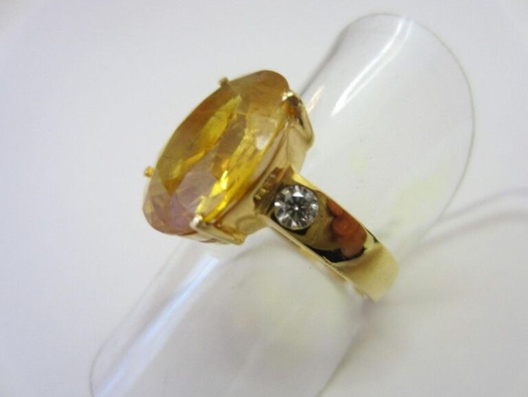 BAGUE en or jaune (750 millièmes) serti d'un saphir jaune de forme ovale épaulé de deux diamants taille brillan