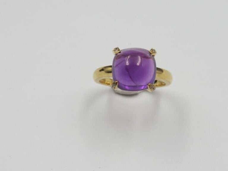 BAGUE en or jaune (750 millièmes) serti d'une améthyste cabochon de forme cousin épaulée de quatre griffes serties de diamants taille brillan