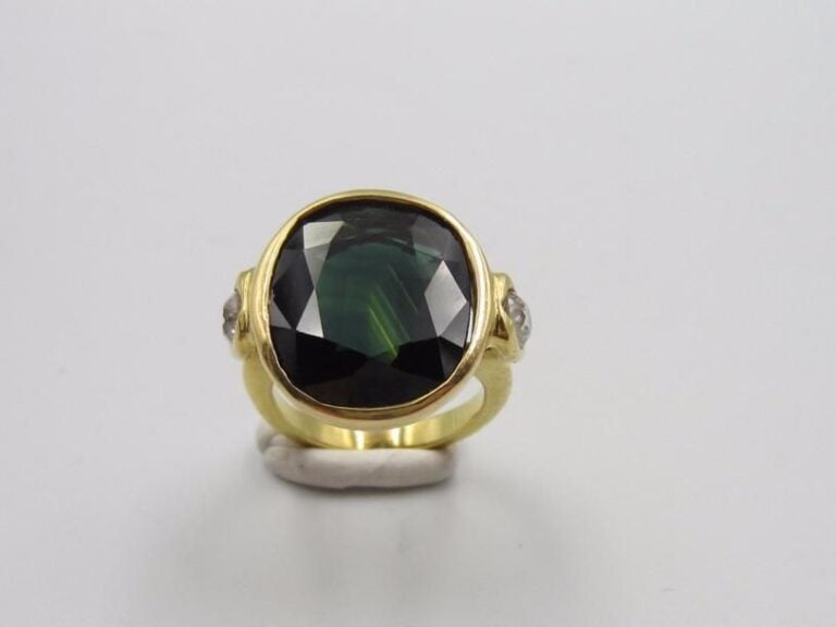 BAGUE en or jaune (750 millièmes) serti d’un important saphir de forme coussin épaulé de deux diamants taille ancienn