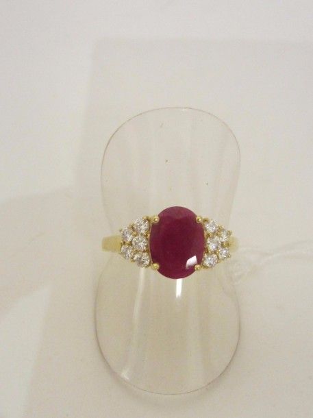 BAGUE en or jaune (750 millièmes) serti d’un rubis de forme ovale pesant 1,24 carat épaulé de cinq diamants taille brillant de chaque côt