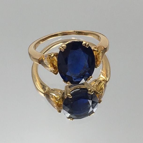 BAGUE en or jaune (750 millièmes) serti d’un saphir de forme coussin épaulé de deux saphirs jaunes de forme poir