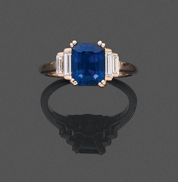 •BAGUE en or jaune (750‰) serti d'un saphir rectangulaire taillé à degrés, épaulé de diamants baguette