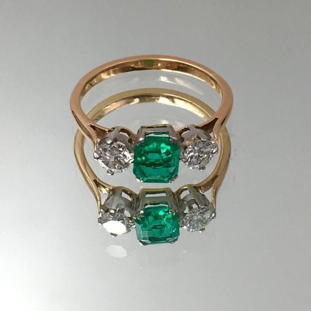 BAGUE en or jaune et or gris (750 millièmes) centré d'une émeraude rectangulaire taillée à degrés épaulée de deux diamants taille brillan