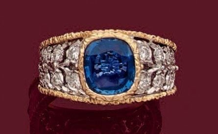BAGUE en or jaune et or gris (750 millièmes) entièrement ciselé et ajouré à motif végétal, serti au centre d'un saphir taille coussin épaulé de diamants taille brillan