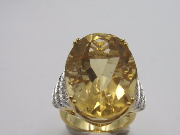 BAGUE en or jaune et or gris (750 millièmes) godronné serti d’une importante citrine de forme ovale pesant 23,3 carats, épaulée de diamants taille brillan