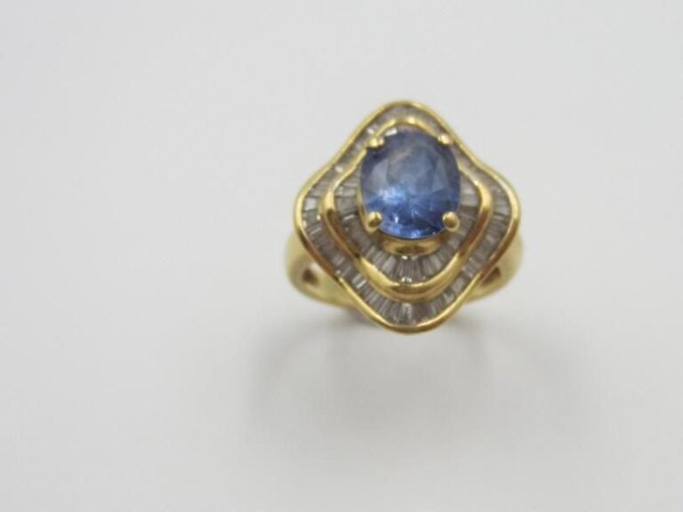 BAGUE en or jaune juponné (750 millièmes) serti d'un saphir de forme coussin dans un double entourage de diamants taeper