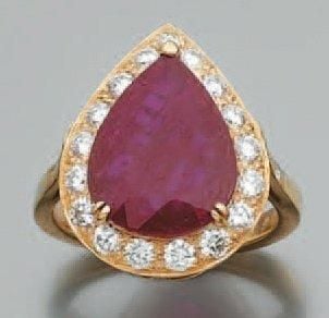 BAGUE en or jaune serti d'un important rubis de forme poire (traces de traitements) entouré de diamant