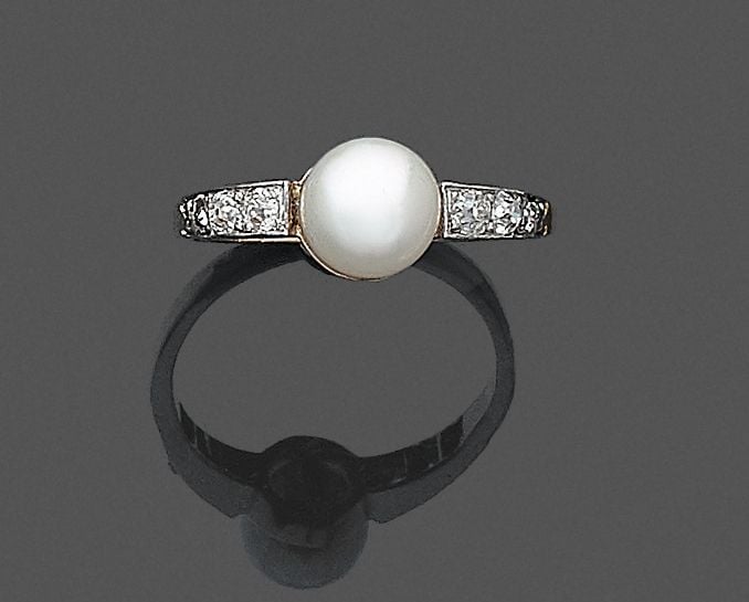 •BAGUE en platine (800‰) et or jaune (750‰) ornée d'une perle (non testée) de forme bouton, de couleur crème, épaulée de six diamants taille ancienn