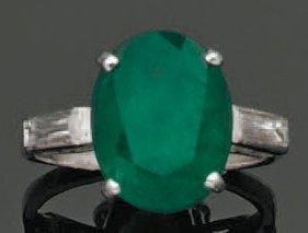 BAGUE en platine serti d'une émeraude de forme ovale épaulée de deux diamants baguette