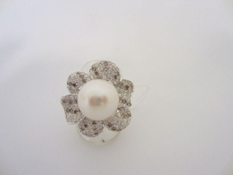 BAGUE «fleur» en or gris (750 millièmes) ajouré serti d?un pavage de diamants taille brillant ponctués de diamants bruns et retenant en son centre une importante perle de culture des Mers du Su