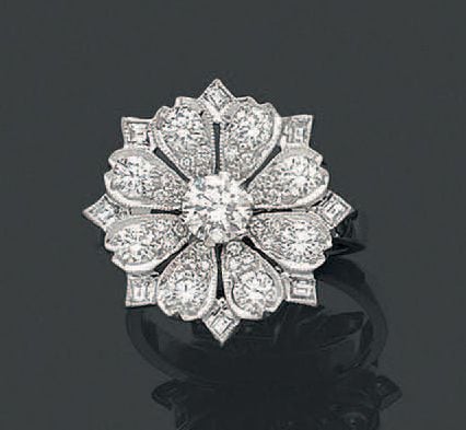 BAGUE «fleur» en or gris (750 millièmes) finement ajouré serti de diamants taille brillant dont un, au centre, plus important et diamants taille émeraud