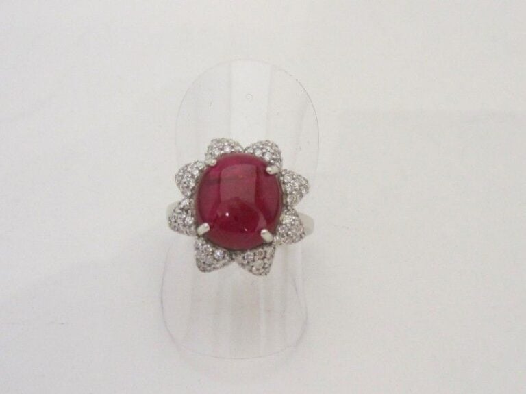 BAGUE « fleur » en or gris (750 millièmes) serti d’un rubis cabochon de forme ovale entouré de pavages de diamants taille brillan