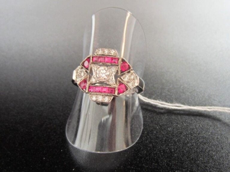 BAGUE géométrique en or gris (750 millièmes) ajouré serti de diamants taille brillant dont un, au centre, plus important rehaussé de rubis calibré