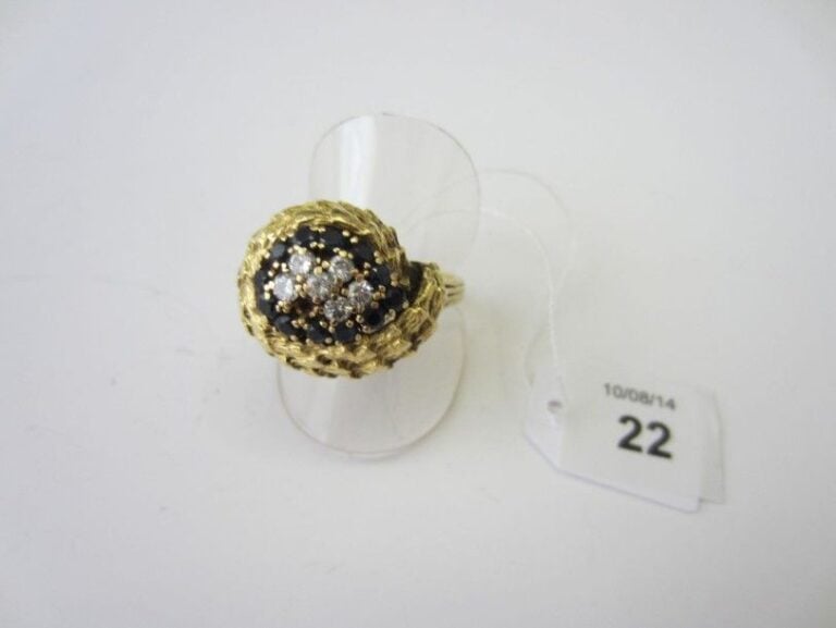 BAGUE «goutte stylisée» en or jaune (750 millièmes) ciselé et bombé, partiellement pavée de diamants taille brillant et saphirs rond