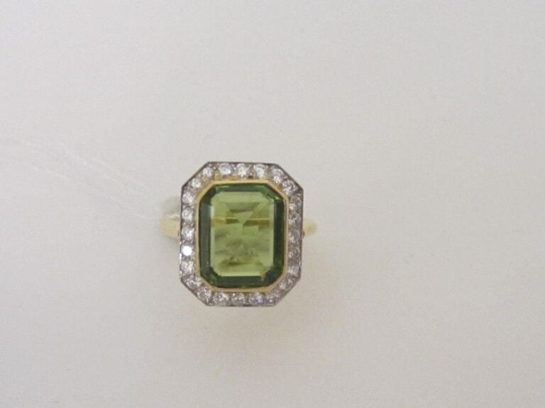 BAGUE hexagonale en or jaune et or gris (750 millièmes) serti d'un péridot de forme rectangulaire entouré de diamants taille brillan
