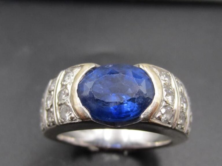 BAGUE jonc en or gris (750 millièmes) serti d'un saphir NON CHAUFFÉ de forme ovale pesant 3,68 carats (égrisures) épaulé de lignes de diamants taille brillan