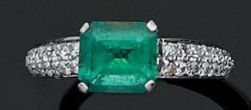 BAGUE jonc en or gris ajouré serti d'une émeraude taillée à degrés épaulée d'un pavage de diamants brillan