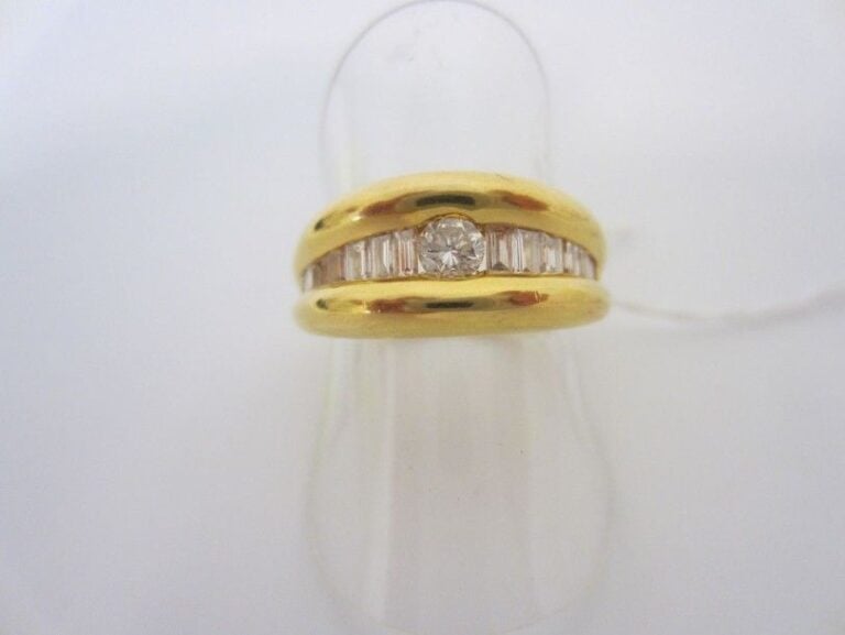 BAGUE jonc en or jaune (750 millièmes) ornée d'un diamant central épaulé de lignes de diamants baguette
