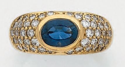 BAGUE jonc en or jaune (750 millièmes) serti d'un saphir de forme ovale entourée d'un pavage de diamants taille brillan